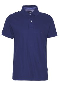 Polo shirt bleu marine en coton avec un col à deux boutons, des manches courtes et un petit logo sur la poitrine. Texture lisse.