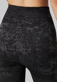 Leggings neri a vita alta con un motivo testurizzato, caratterizzati da una leggera lucentezza e un logo Calvin Klein sulla vita.