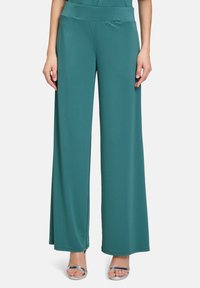 Teal wide-leg pants made of smooth fabric with a high waistband, featuring full-length legs and a clean, minimalist design. Silver heels included.