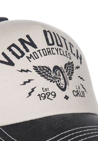 Pelēka auduma cepure ar melnu logo, ar uzrakstu "VON DUTCH MOTORCYCLES," spārnu riteņa dizainu un gada "Est. 1929" treknās burtnēs. Melns vizieris.