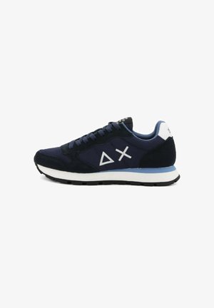 Zapatilla azul marino con superposiciones de ante negro, suela blanca y logo de triángulo y cruz blanca en el costado, vista desde el lado exterior.