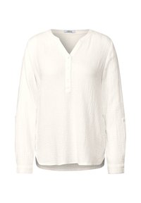 Hvid skjorte med lange ærmer i et tekstureret stof. Har V-hals, knaplukning og ærmer, der kan rulles op med knapdetaljer.