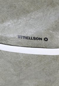 Prodotto in pelle grigia strutturata con una striscia bianca e il logo nero "STRELLSON". La superficie mostra pieghe e variazioni nella texture.