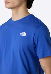Blå crew-neck t-shirt lavet af blød bomuld, med et lille hvidt logo på brystet. Korte ærmer og en klassisk pasform.