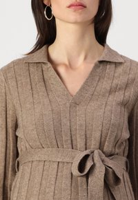 Braunes, geripptes Strickkleid mit V-Ausschnitt und Kragen, ausgestattet mit einem taillierten Gürtel und strukturiertem Stoff.