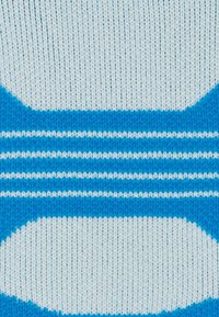 Primo piano di un tessuto lavorato a maglia con strisce orizzontali bianche e blu alternate e forme ovali.