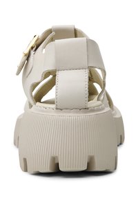 Sandale beige à semelle épaisse, larges brides en cuir et boucle dorée, vue de dos sur fond blanc.