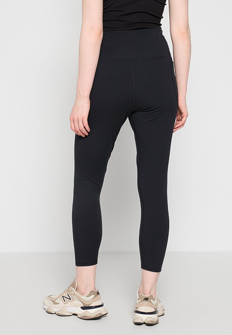 Leggings neri realizzati in tessuto elasticizzato, con una vita alta e un design aderente che si estende fino a metà polpaccio.