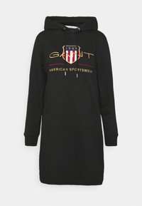 Robe sweat à capuche noire avec une poche frontale. Présente un logo brodé en doré et rouge, avec une coupe décontractée et des poignets côtelés.