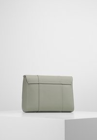 Borsa in pelle sintetica verde con una forma rettangolare elegante, dotata di una patta pieghevole e dettagli verticali cuciti. Inclusa chiusura a zip.