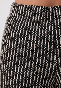 Close-up of black and white vertically striped textured knit fabric on a high-waisted garment.