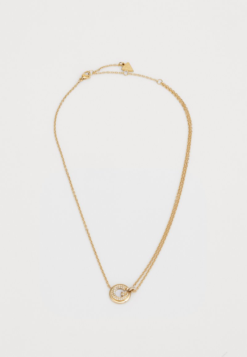 Collier en or avec deux chaînes, orné d'un pendentif circulaire décoré de petites pierres transparentes et d'une lettre "G" au centre.