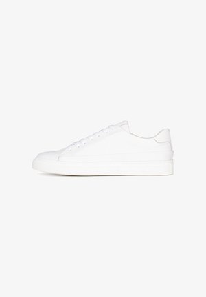 Zapatilla blanca de tipo bajo con suela gruesa, cierre de cordones y parte superior de cuero suave, mostrada de perfil sobre un fondo blanco.