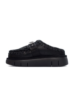 Scarpe nere slip-on con tomaia in pelle testurizzata, dettagli cuciti e suola in gomma con scanalature distinte. Accentato con una fibbia sulla cinghia.
