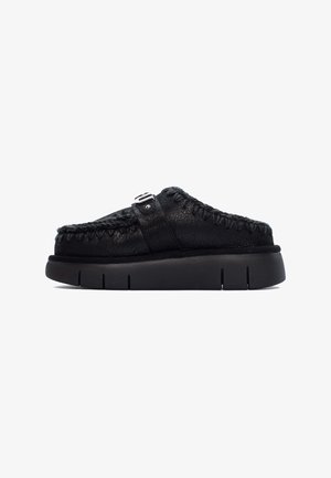 Scarpe nere slip-on con tomaia in pelle testurizzata, dettagli cuciti e suola in gomma con scanalature distinte. Accentato con una fibbia sulla cinghia.