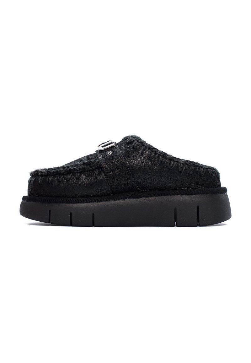 Scarpe nere slip-on con tomaia in pelle testurizzata, dettagli cuciti e suola in gomma con scanalature distinte. Accentato con una fibbia sulla cinghia.