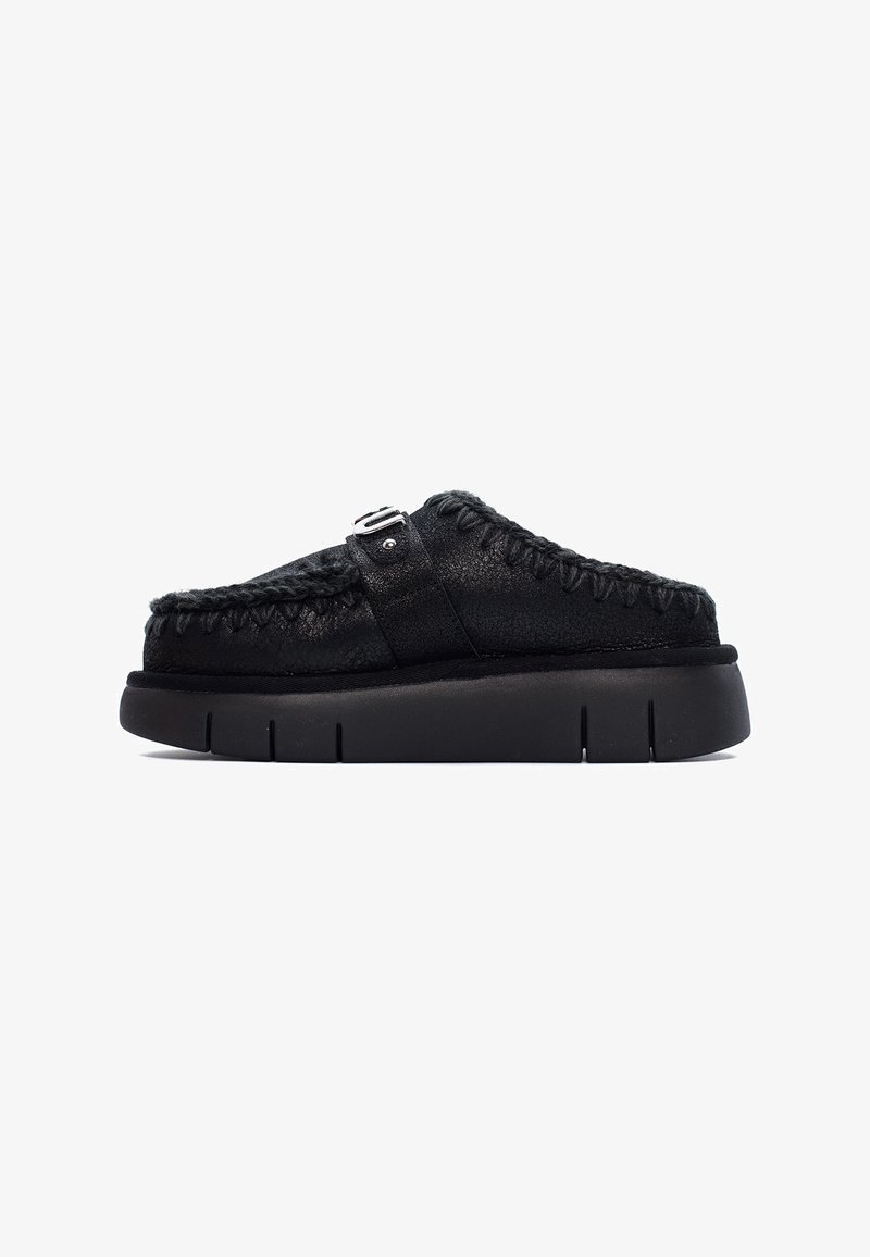 Scarpe nere slip-on con tomaia in pelle testurizzata, dettagli cuciti e suola in gomma con scanalature distinte. Accentato con una fibbia sulla cinghia.