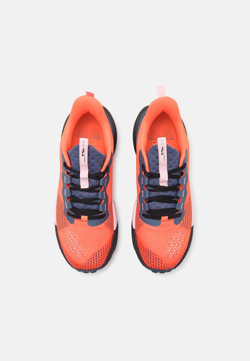 Zapatillas deportivas de un brillante color naranja con una textura perforada, cordones azul marino y suelas negras. Presentan una tira de tiro en color rosa en el talón.