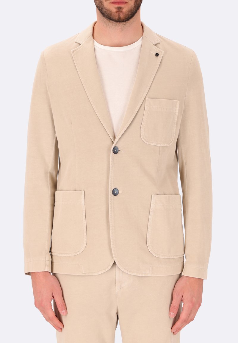 Blazer in cotone beige con rever a punta, due tasche frontali e due bottoni. Presenta una finitura testurizzata e un design pulito e minimalista.
