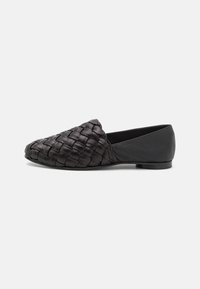 Černá pletená slip-on bota s texturovaným svrškem, s špičatou špičkou a plochým podpatkem, doplněná hladkým koženým zadním dílem.