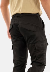Sorte cargo bukser med slim fit, der har baglommer, glat tekstur og flad talje, designet til funktionalitet og komfort.