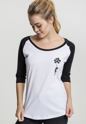 White and black long-sleeve t-shirt featuring a rounded neckline. Black sleeves, front graphic of a child with balloons. Soft cotton material.