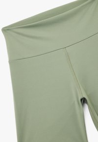 Höga, olivgröna leggings tillverkade av elastiskt tyg med en slät textur och synliga sömmar längs sömmarna.