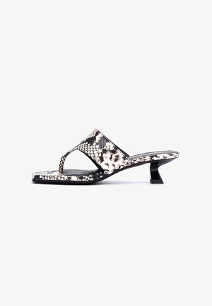Sandales à imprimé serpent noir et blanc avec une bride fine et un petit talon bloc, présentant une surface texturée et un design à bout ouvert.