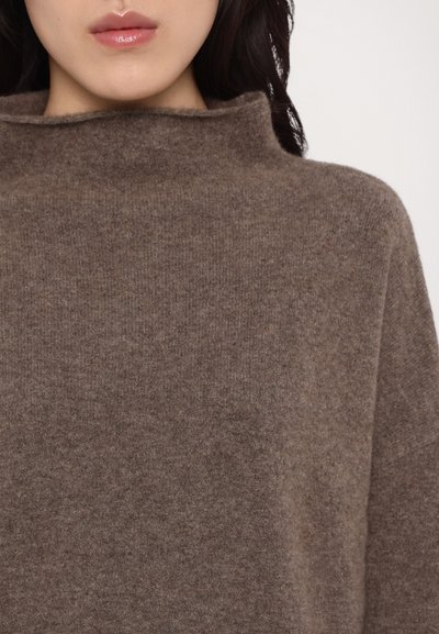 Brun ullgenser med høy hals, myk tekstur og avslappet passform. Stoffet viser et subtilt, jevnt kornmønster.