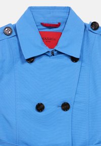 Μπλε καμπαρντίνα με μυτερό γιακά, διπλό κούμπωμα, μαύρα κουμπιά και κόκκινη εσωτερική ετικέτα. Ομαλή υφή και καθαρό ράψιμο.