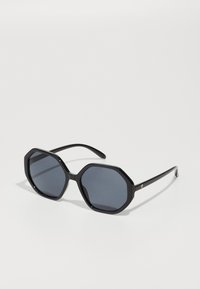 Ochelari de soare octagonali negri cu lentile întunecate. Ramă din plastic elegantă, cu textură netedă și brațe subțiri, având un mic logo pe o parte.