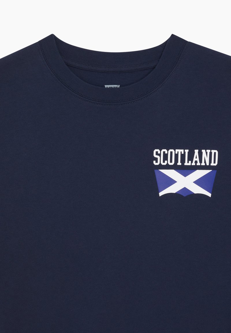Tamnoplava majica s okruglim izrezom i natpisom "SCOTLAND" te bijelo-plavom zastavom Saltire otisnutom na lijevoj strani prsa.
