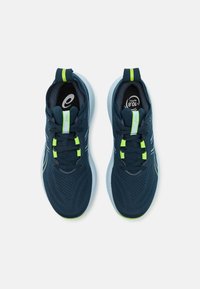 Scarpe da ginnastica di colore blu scuro realizzate in materiale mesh con suole di un turchese chiaro. Presentano dettagli di accenti verdi neon e strisce riflettenti.