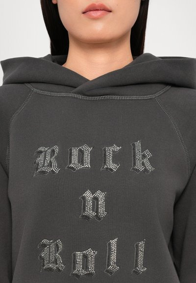Pelēks kapuces krekls ar uzrakstu "Rock n Roll", kas izrotāts ar rhinestones. Mīksta kokvilnas sajaukuma audums ar teksturētām šuvēm.