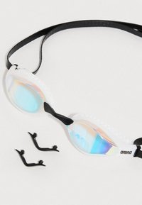 Γυαλιά κολύμβησης με διάφανα φακούς μπλε απόχρωσης, λευκό πλαίσιο από σιλικόνη και μαύρη λουράκι. Περιλαμβάνει δύο μαύρα κλιπ ρύθμισης.