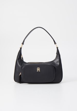 Czarna skórzana torba na ramię z przednią kieszenią na zamek oraz złotym logo "TH", pojedynczym, zakrzywionym paskiem i górnym zamkiem błyskawicznym.