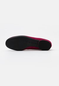 Fuchsia suede shoe with a rounded toe, black rubber sole, and textured bottom for grip. No visible hardware or embellishments.
