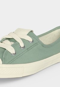 Χαμηλά sneakers από μουσελίνα σε υποτονικό πράσινο χρώμα με παχιά λευκά κορδόνια, λευκή ελαστική σόλα και επενδεδυμένη εσωτερική επένδυση.