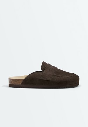 Mocassino marrone in camoscio slip-on con suola in sughero e tacco basso, con dettaglio di cinturino cucito sulla parte superiore.