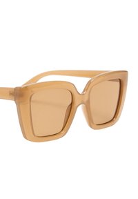 Brązowe, oversize okulary przeciwsłoneczne o kwadratowym kształcie, wykonane z przezroczystego materiału, z szerokimi zausznikami i przyciemnionymi soczewkami.