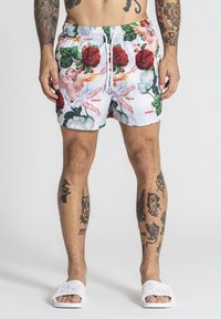 Shorts de bain pour hommes avec une base blanche, ornés d'un imprimé floral et de chérubins éclatants. Taille élastique avec cordon de serrage ; design longueur genou.