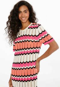 Pletené šaty s cik-cak vzorem v korálové, růžové, bílé a černé barvě, krátké rukávy a volný střih. Texturovaný, žebrovaný materiál.