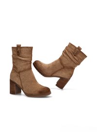 Botas de tobillo de ante marrón con un diseño suelto, punta redondeada y tacón cuadrado de 3 pulgadas. Presentan un acento de botón en el puño y costuras en contraste.