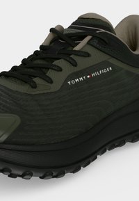 Σκούρο πράσινο και μαύρο sneaker Tommy Hilfiger με μαύρα κορδόνια, υφασμάτινη υφή και παχύ ραβδωτό πάτο.