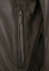 Dunkelgrüne Lederjacke mit einem sichtbaren Metallreißverschluss am linken Ärmel, mit einer glatten Textur und robusten Nähdetails.