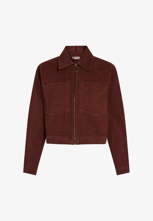 Samtjacke in tiefrot, mit langen Ärmeln, spitzem Kragen, zwei Vordertaschen und einem zentralen Reißverschluss mit einem runden Ziehgriff.