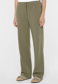 Olivengrüne weit geschnittene Hose aus weichem Stoff, mit Knopfverschluss, seitlichen Reißverschlusstaschen und glatter Textur.