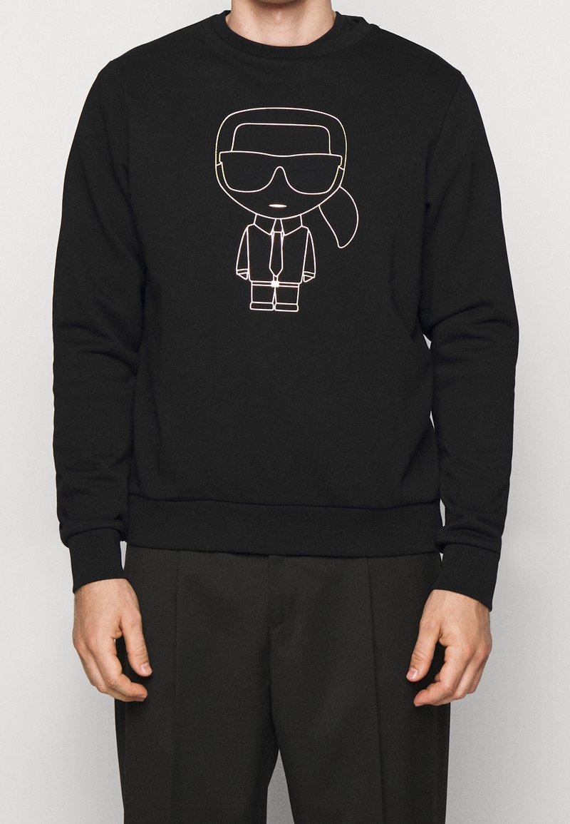 Sudadera negra con un gráfico de un personaje de dibujos animados con gafas de sol y traje, contorneado en multicolor, de material suave y con cuello redondo.