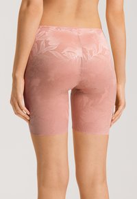 Rosa blommönstrade lace-shorts med en texturerad design. Plagget har en figurnära passform och sträcker sig till mitten av låret. Mjuk, semi-genomskinlig tyg.