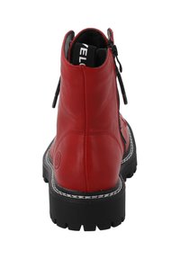 Stivaletto alla caviglia in pelle rossa con suola in gomma nera, dotato di cerniera posteriore, cuciture decorative e un'etichetta con logo all'apertura.